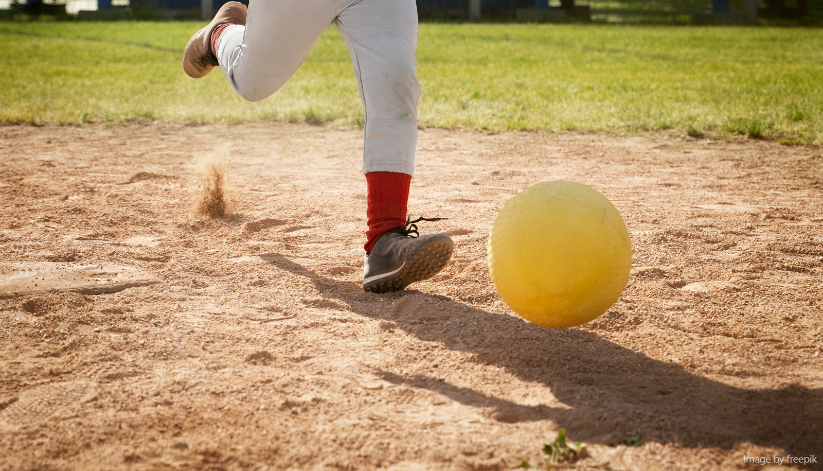 Cleat kicking yellow kickball on field